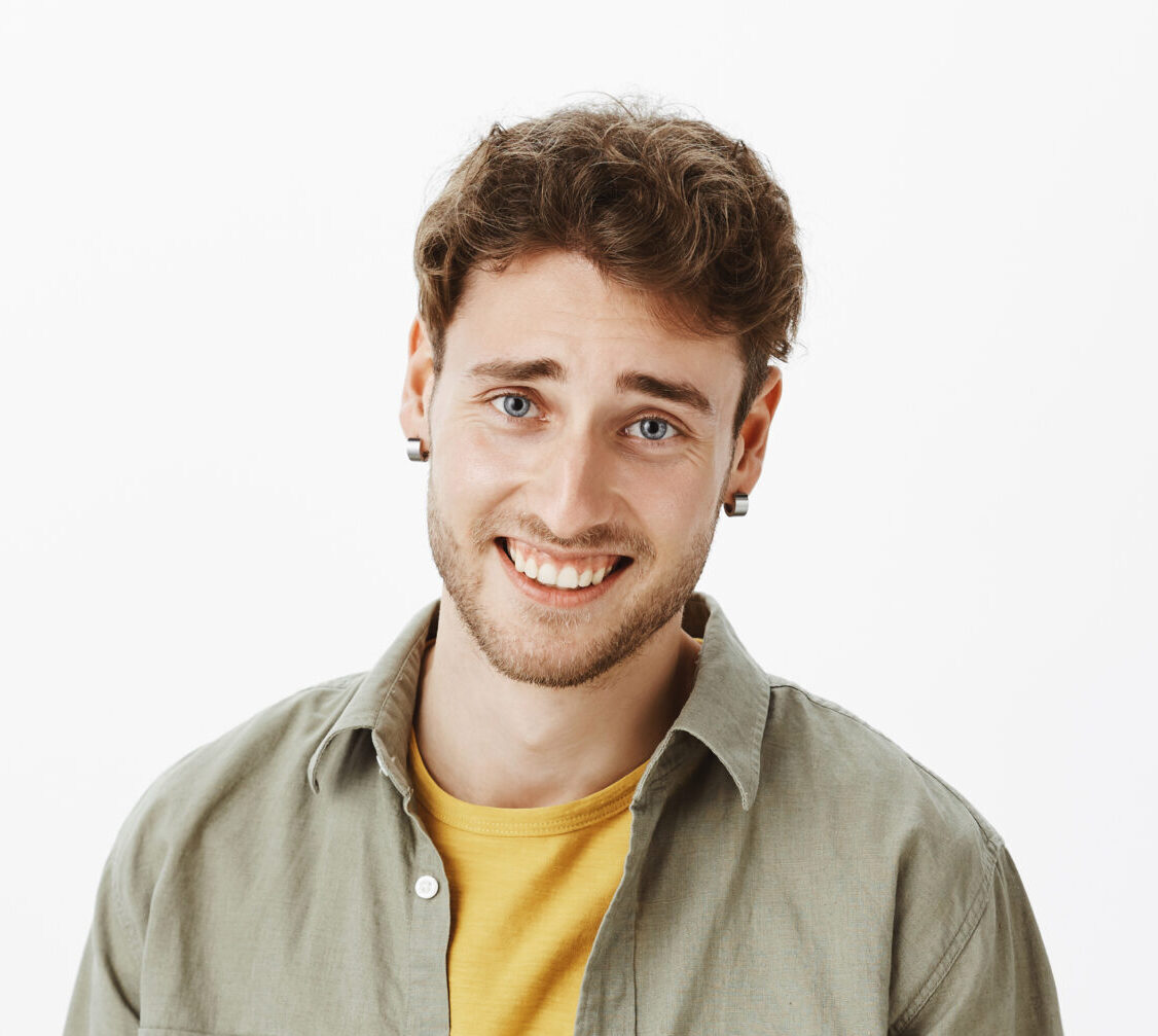 Home waist up shot of arrogant handsome and self assured curly haired male with bristle, laughing and looking wish disdain at camera, standing over gray background careless and indifferent